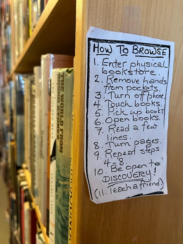 Close-up of a handwritten list taped to a bookshelf. List starts HOW TO BROWSE & includes 1) Enter physical bookstore...3) Turn off phone. 10) Be open to DISCOVERY!